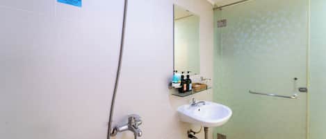 A bathroom with a shower, sink, and a glass-enclosed shower stall.