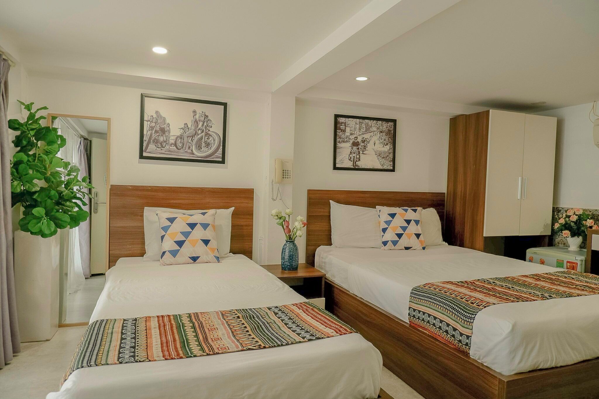 A hotel room with two beds, wooden headboards, and a large wardrobe.