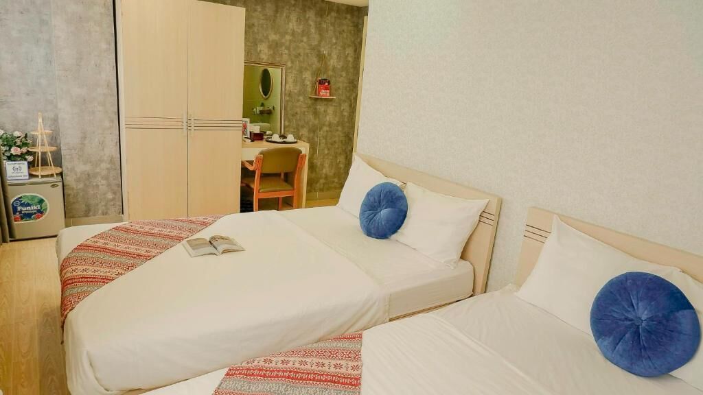 A hotel room with two beds, a desk, and a wardrobe.