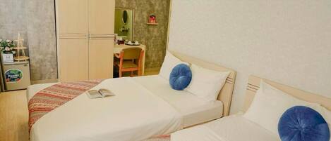 A hotel room with two beds, a desk, and a wardrobe.
