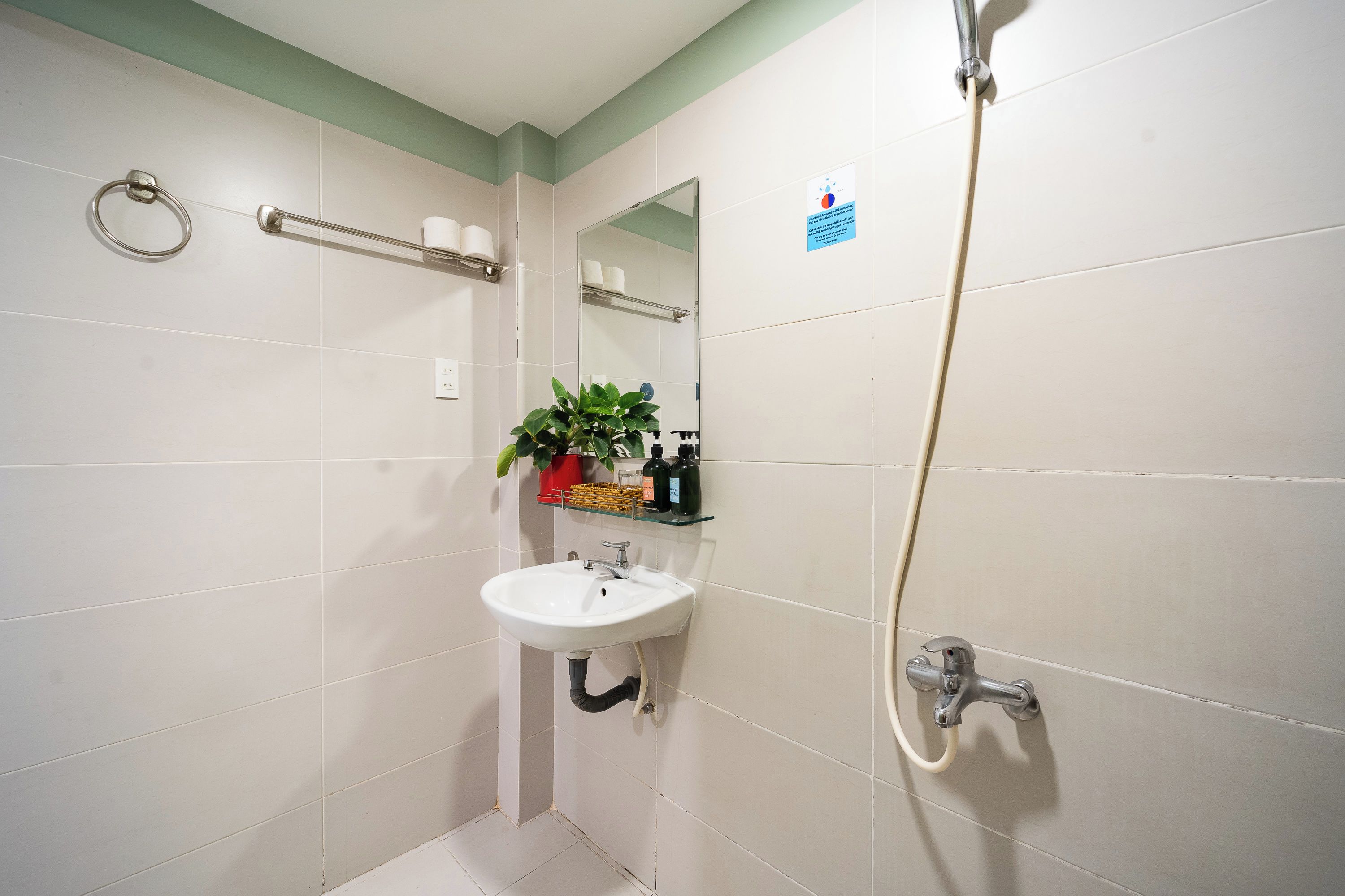 A bathroom with a sink, mirror, towel rack, and shower.