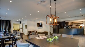 Uma zona de refeições moderna com uma mesa grande, cadeiras e uma luminária pendente geométrica singular.
