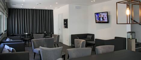 A modern living room with grey sofas, a coffee table, and a flat-screen TV mounted on the wall.
