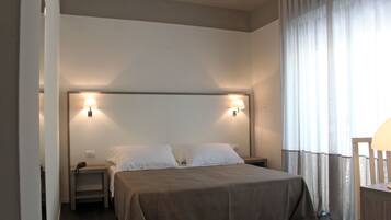 A hotel room with a large bed, two bedside tables, and a nightstand with a lamp.