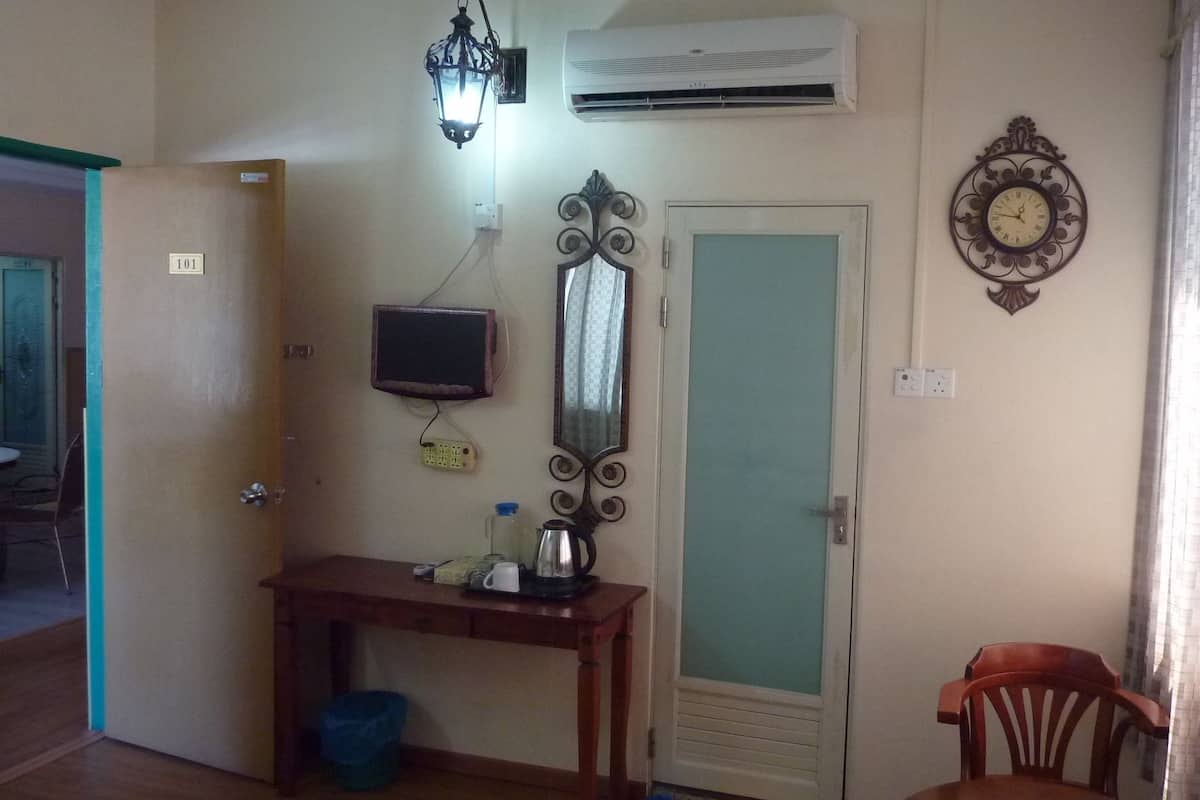 A room with a desk, a mirror, a wall clock, an air conditioner, and a door.