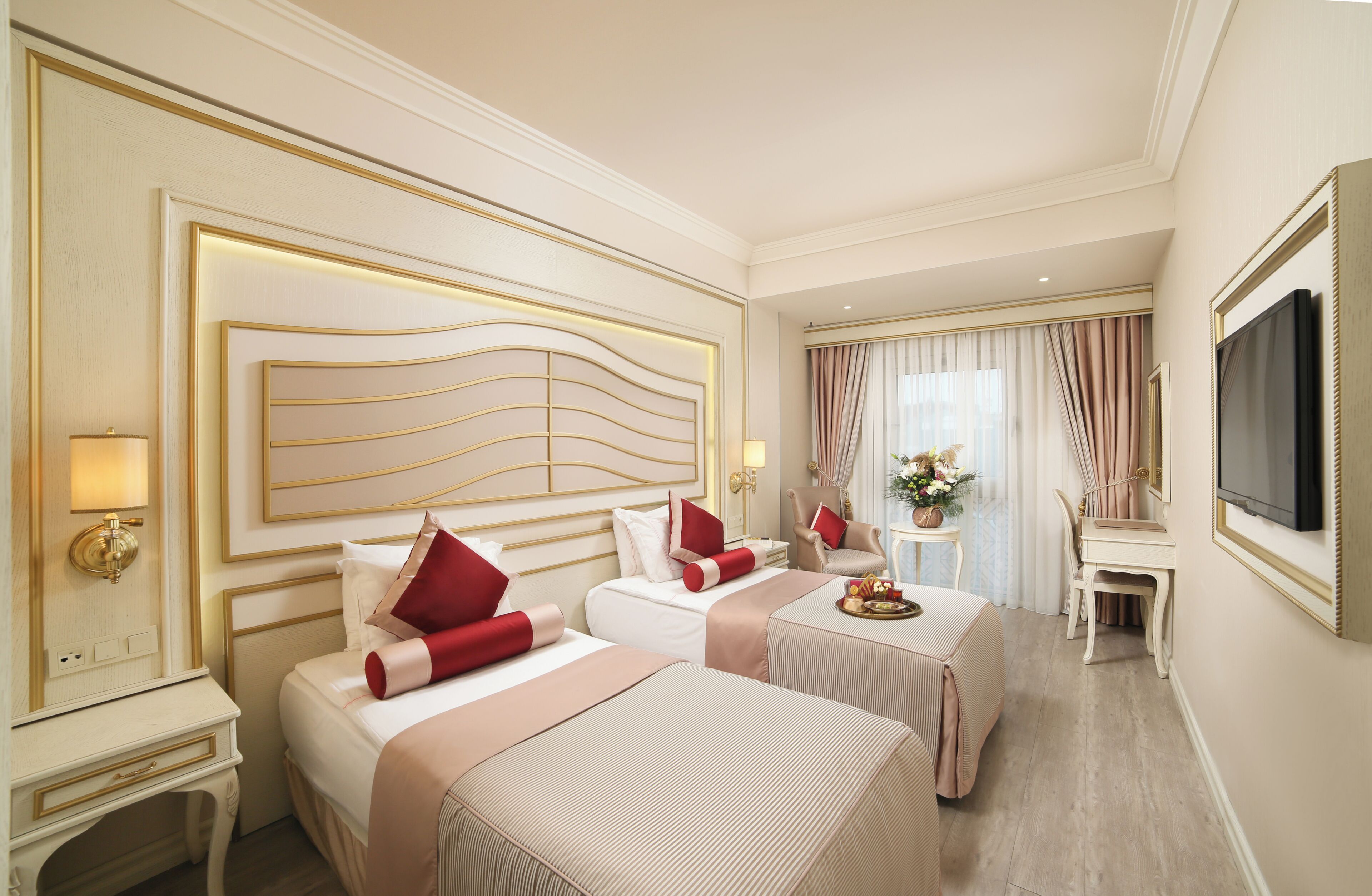 Une chambre d’hôtel avec deux lits, un bureau, une télévision et une fenêtre avec des rideaux.