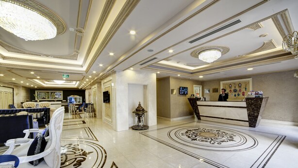 En hotellobby med en receptionsdisk, en sittgrupp och dekorativa element.