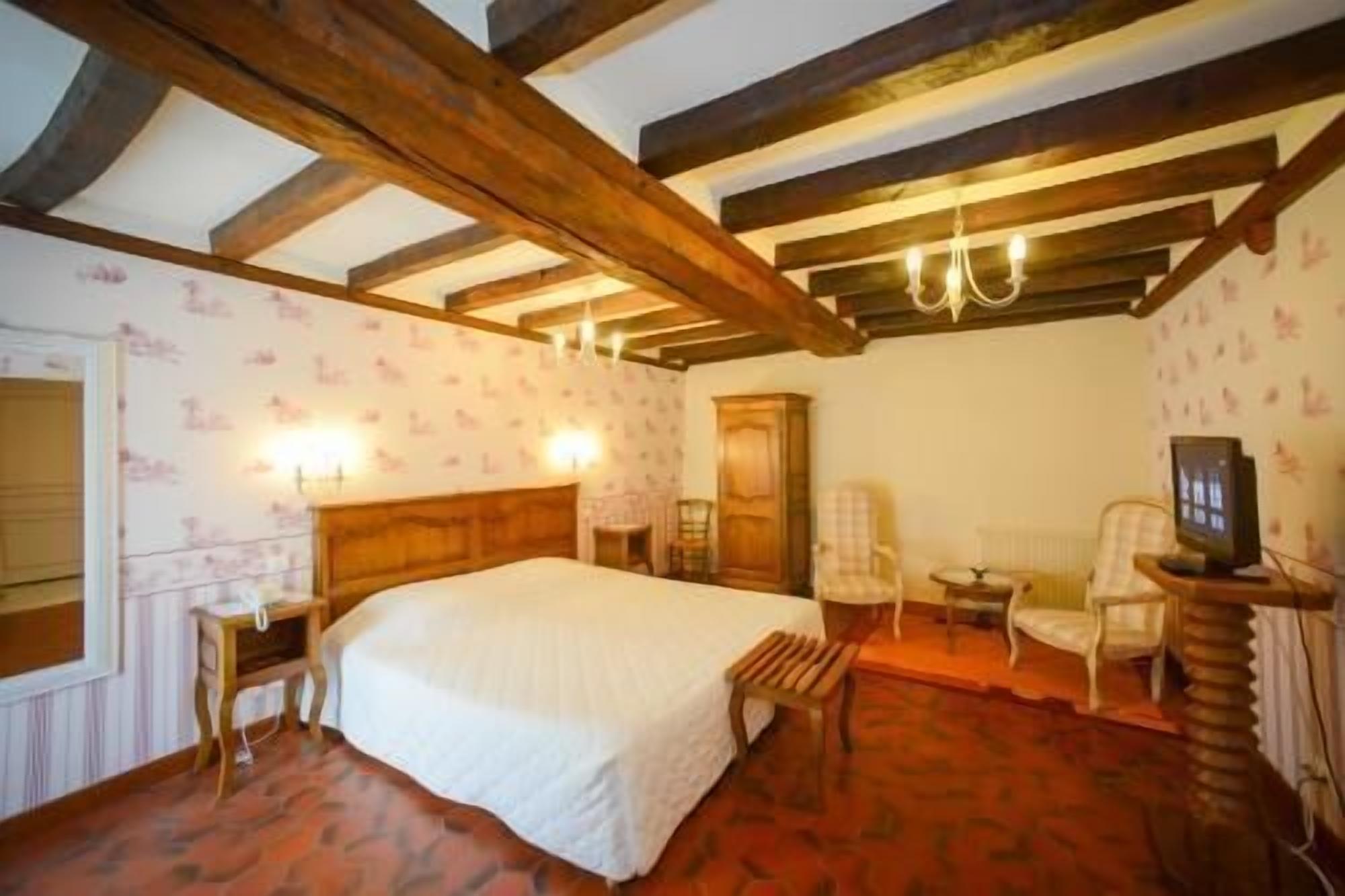 Une chambre avec un plafond en bois, un lit, un bureau, une chaise et un téléviseur.