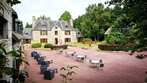 Un bâtiment en pierre doté d’une cour, d’un espace extérieur aménagé pour s’asseoir et d’un jardin.