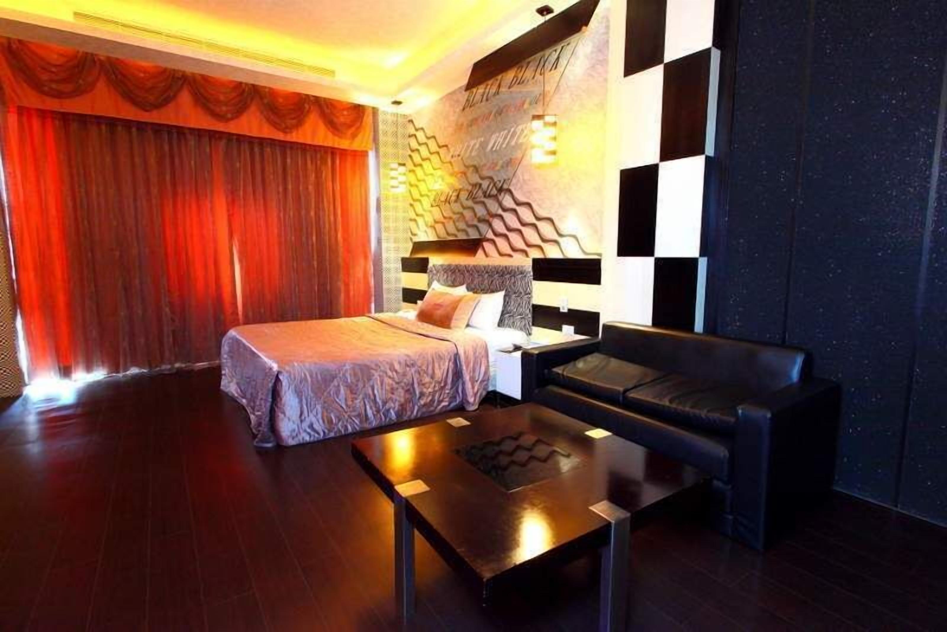 Une chambre d’hôtel moderne, équipée d’un lit, d’un canapé, d’une table basse et d’un mur décoratif orné de motifs géométriques.