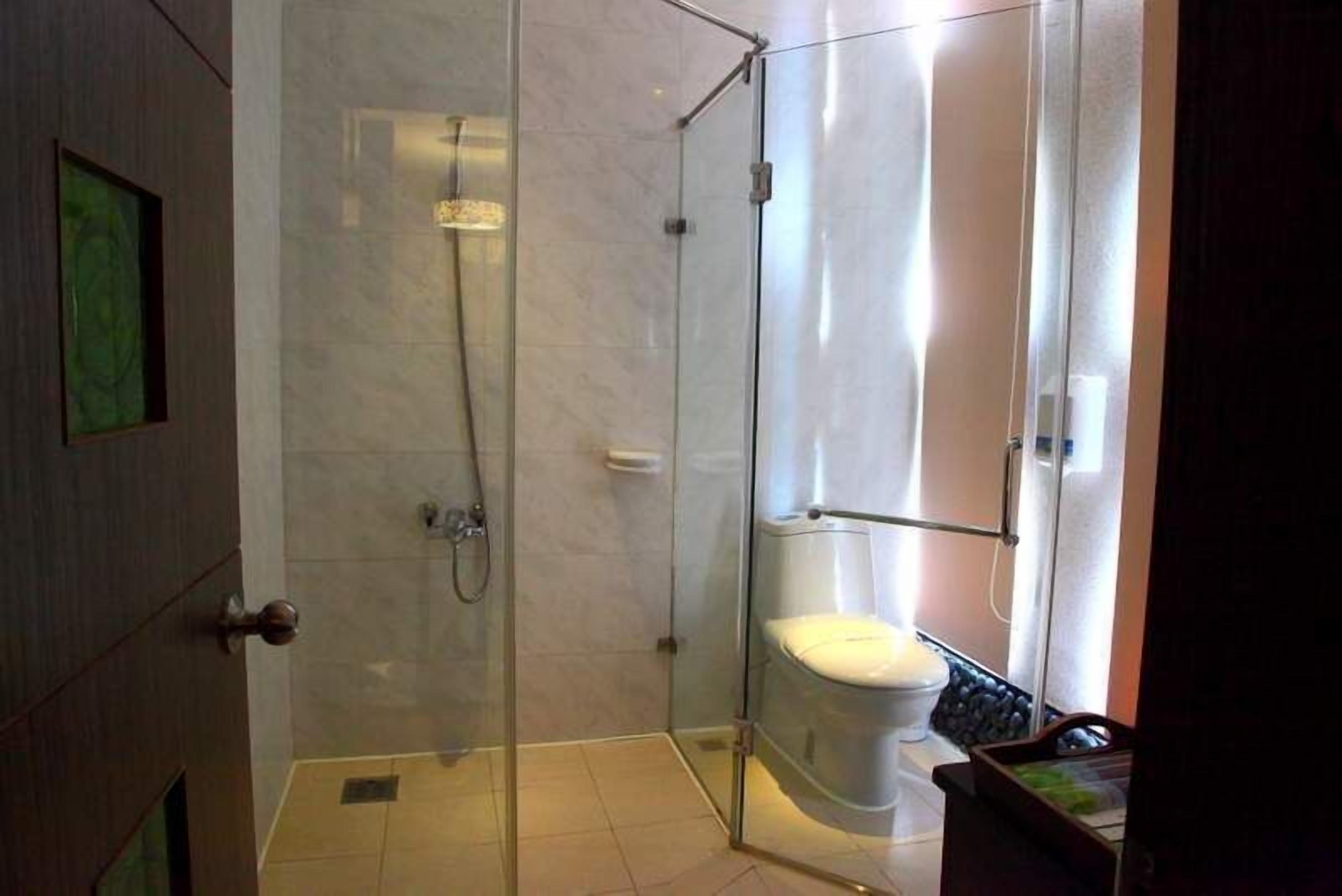 Een moderne badkamer met een douche met glazen wand, een toilet en een wastafel.