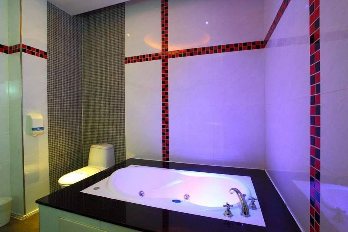 A modern bathroom with a black countertop, a white bathtub, and a toilet.
