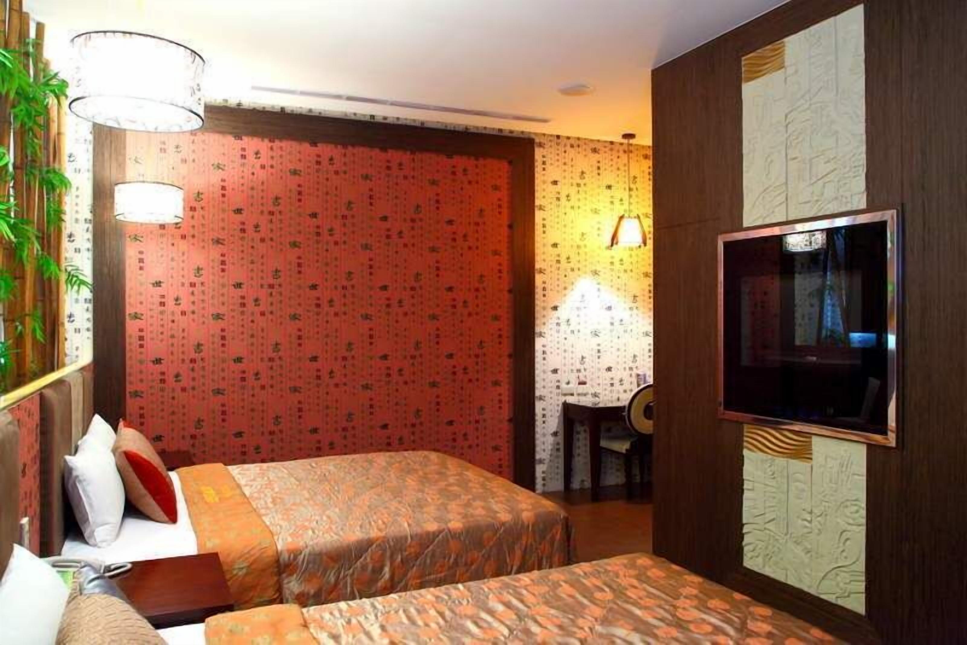 A hotel room with two beds, a TV, a desk, and a chair.