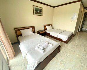 A hotel room with two beds, a wooden headboard, a nightstand, and a framed picture on the wall.