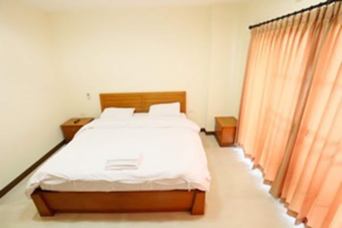 A single bed with a wooden headboard, white bedding, and two bedside tables.