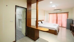 A hotel room with a bed, a desk, a chair, a TV, and a window with curtains. - Noppakao Place (Chiang Mai)