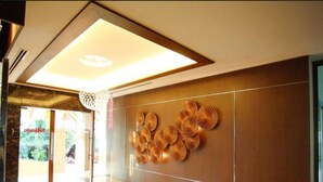 A modern lobby with a polished wooden floor, a ceiling light, and a wall with a circular decorative pattern. - Noppakao Place (Chiang Mai)