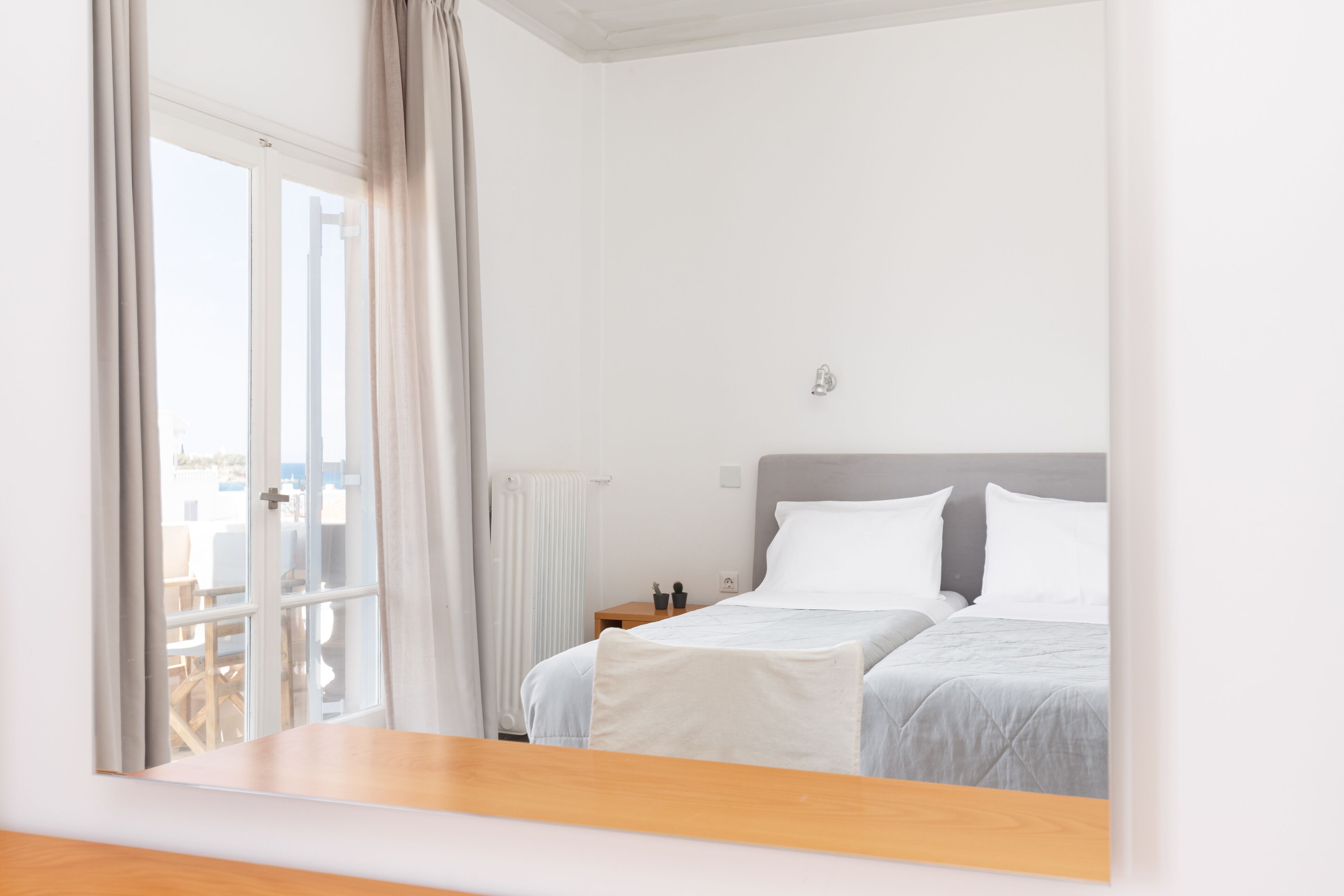 Habitació d'hotel amb un llit, una tauleta de nit, una finestra amb cortines i vista exterior.