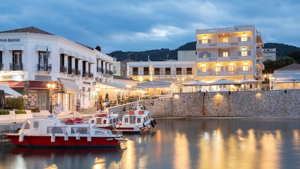 Un hotel frente al agua con varios balcones, una pared de piedra y barcos amarrados al fondo.