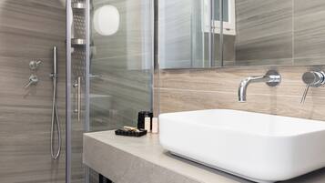 A modern bathroom with a glass shower enclosure, a white sink, and a large mirror.