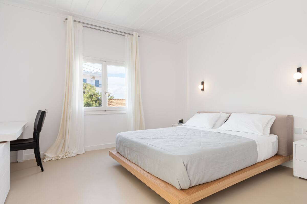 A modern bedroom with a bed, a desk, and a chair.