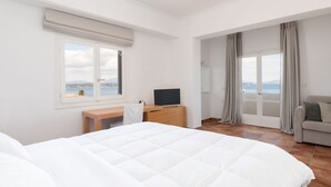 Un dormitorio con cama, un escritorio con televisor, un sofá y vista al mar.