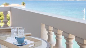 Un balcón con vistas al mar, una mesa con una bandeja, dos vasos y una taza.