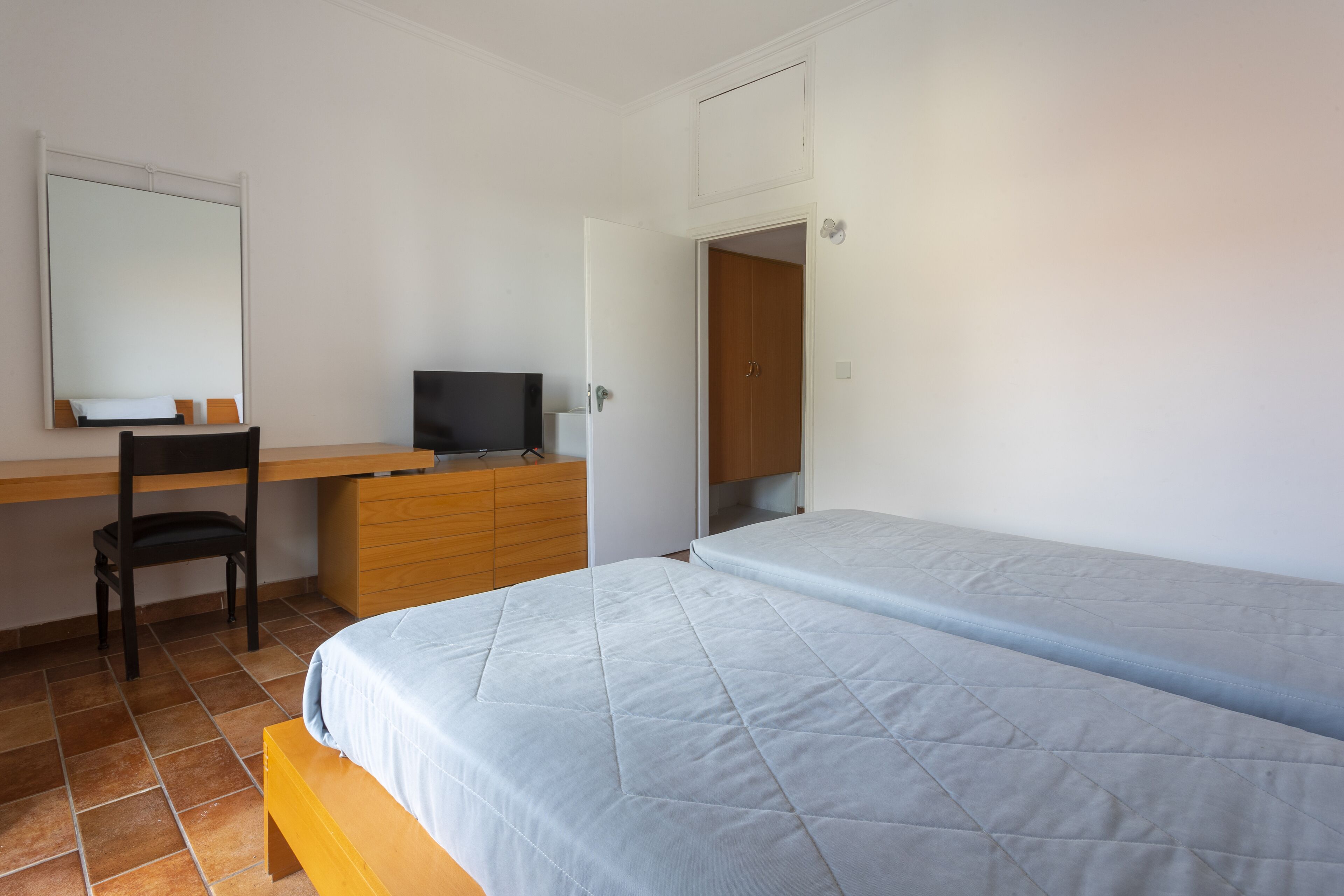 Un dormitorio con cama, escritorio, silla y televisor.