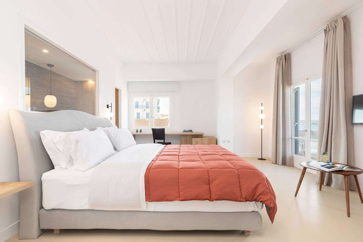 A modern hotel room with a large bed, a desk, and a television.