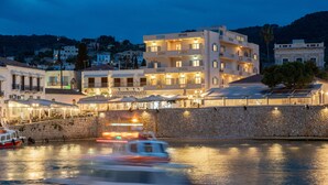 Un hotel frente al agua con varios balcones, un muro de piedra y un barco amarrado.