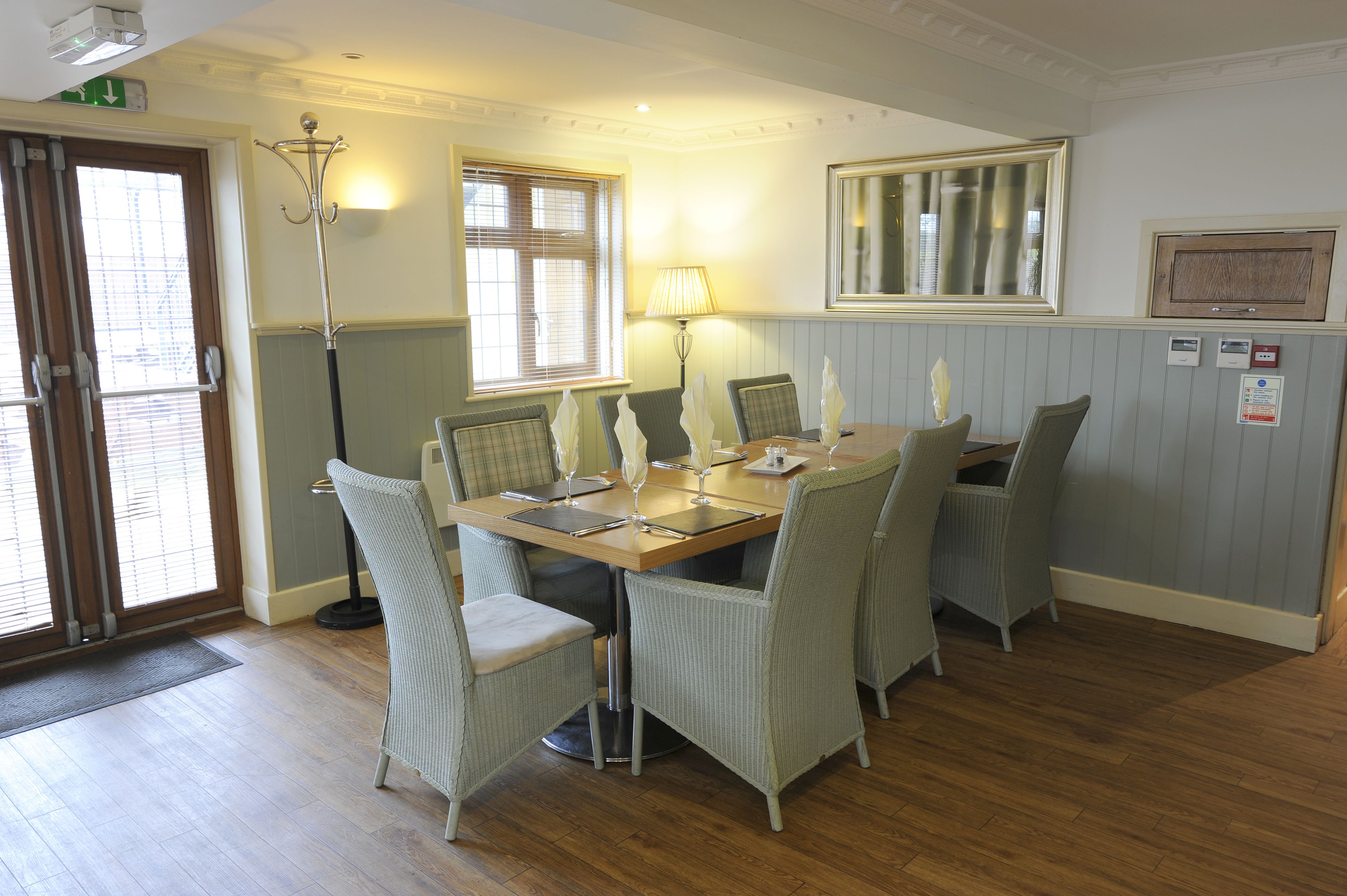 A dining area with a wooden table, six chairs, and a floor lamp.