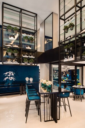 A modern dining area with a glass-top table, blue chairs, and a blue accent wall.