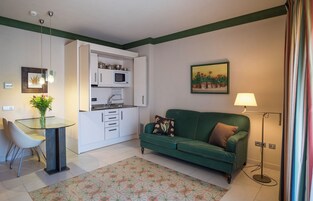 Un espacio habitable compacto con kitchenette, comedor y sofá verde.