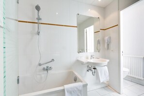 A modern bathroom with a bathtub, a sink, and a toilet. - Hôtel Vendôme (Strasbourg)