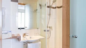 A modern bathroom with a glass shower enclosure, a white sink, and a toilet.
