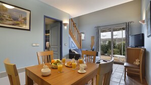 Ein Essbereich mit einem Holztisch, gedeckt für das Frühstück, einer Treppe und Blick ins Freie.