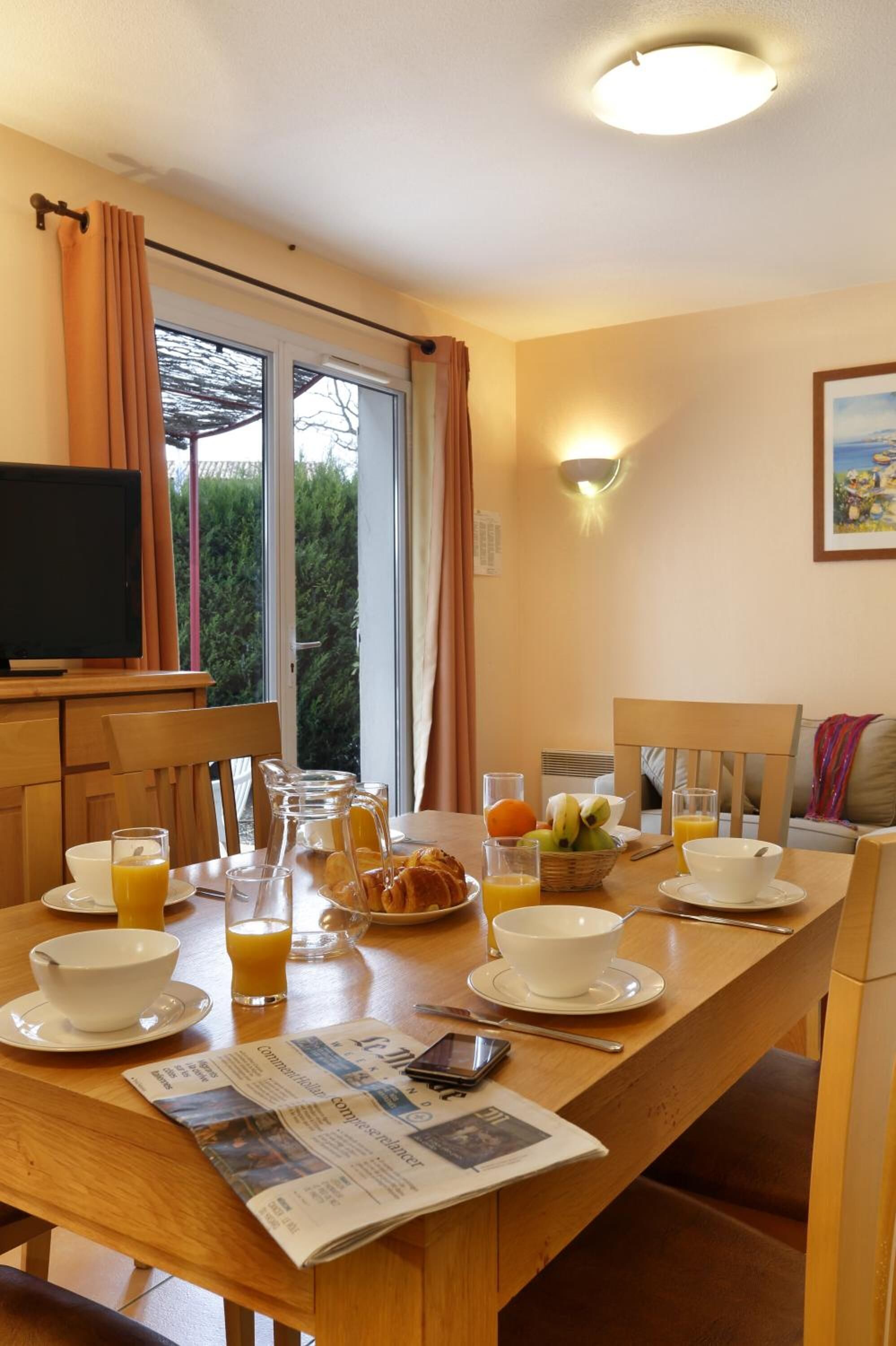A breakfast setup with a table, chairs, breakfast items, and a TV.