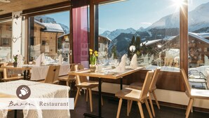 Ein Restaurant mit Holztischen und -stühlen, großen Fenstern mit Blick auf die Berge und einem Schild mit der Aufschrift "Bären Restaurant".