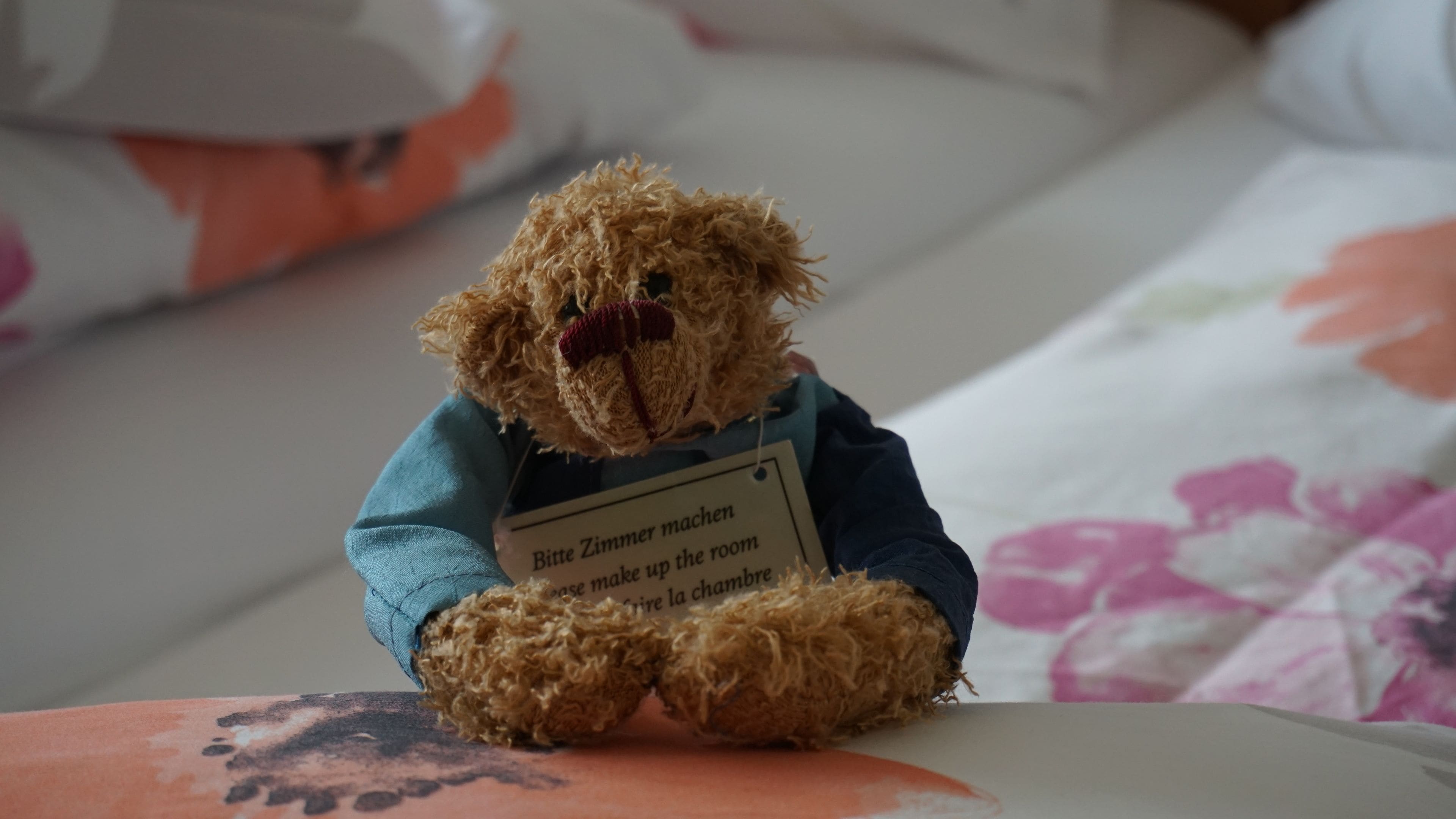 A teddy bear with a tag on a bed.