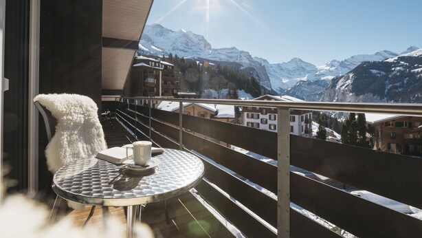 Ein Balkon mit rundem Tisch, einem weißen, flauschigen Sessel und einer Tasse.