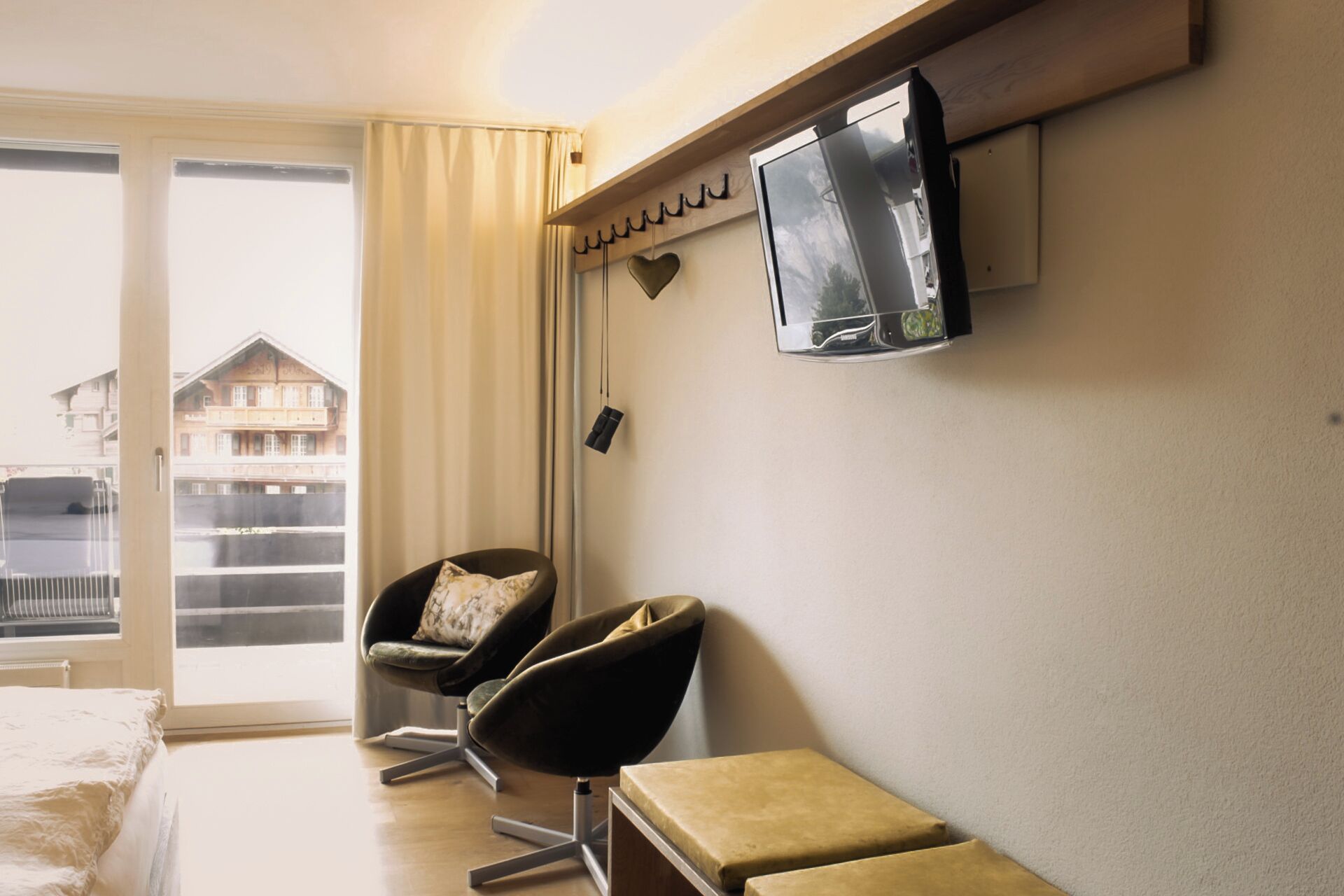 Una camera d'albergo con un letto, due poltrone, una TV a parete e vista sui palazzi.