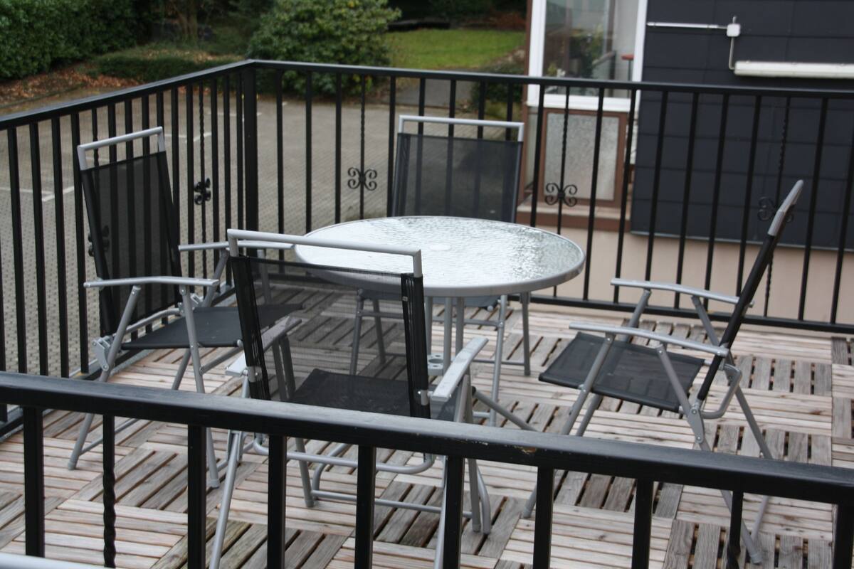 A patio with a round table and chairs, surrounded by a black metal railing.