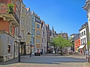 A cobblestone street lined with colorful historic buildings, a central square with trees, and outdoor seating areas. - Platinium Hotel Aachen (Aachen)