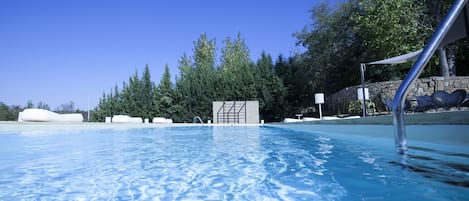 Una piscina al aire libre de temporada, sombrillas