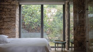 A bedroom with a large window, stone walls, a bed, and a small table. - Masseria Bannata (Enna)