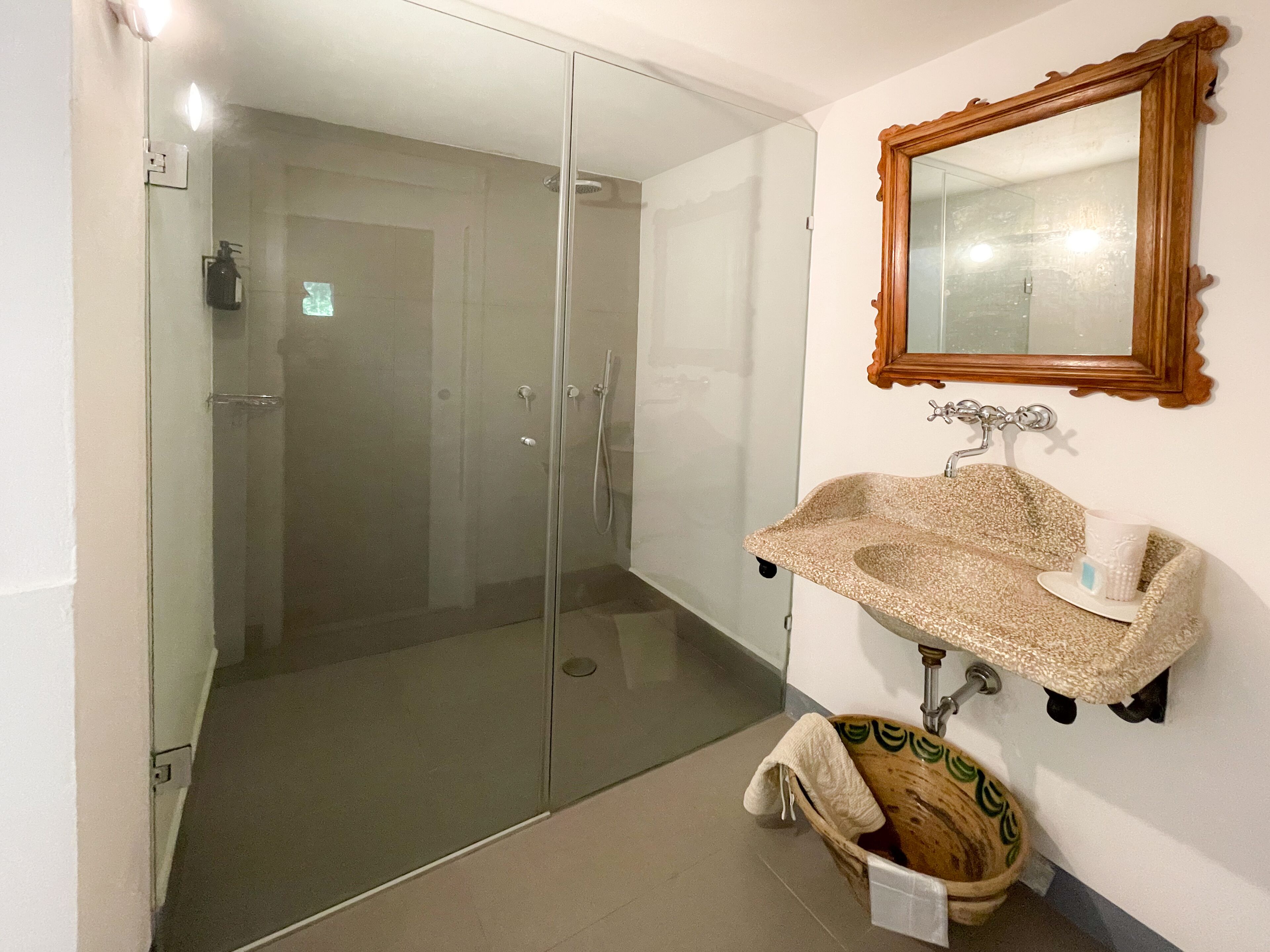 A bathroom with a glass shower enclosure, a sink with a decorative basin, and a wooden bath tub.