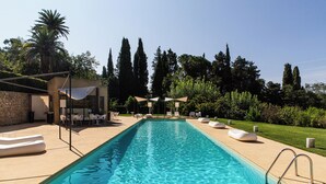 A rectangular swimming pool with clear blue water, surrounded by a beige deck. There are lounge chairs and umbrellas along the poolside. - Masseria Bannata (Enna)