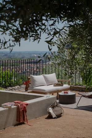 An outdoor seating area with a sofa, a wicker ottoman, and a lounge chair. - MiHotel (Lyon)