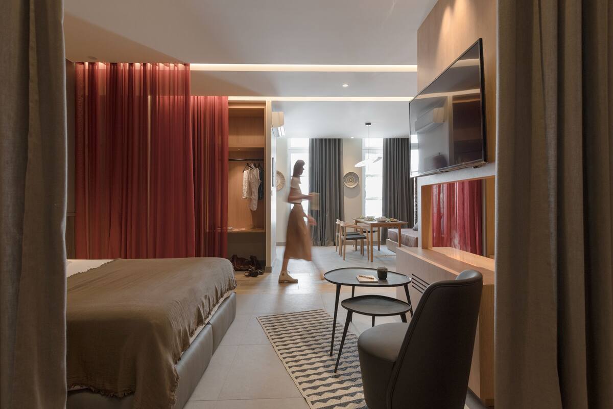 A hotel room with a bed, a desk, a chair, a TV, and a wardrobe.