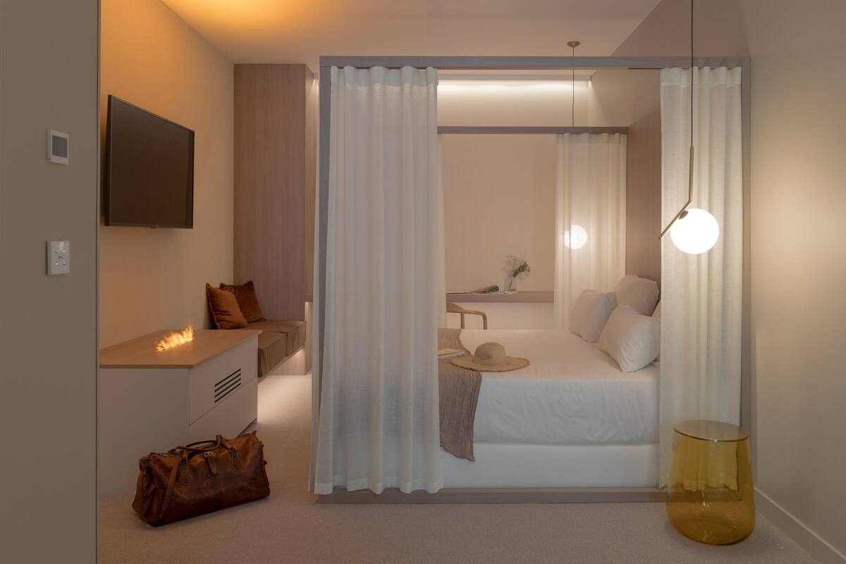 A modern bedroom with a bed, bedside table, and a hanging light fixture.